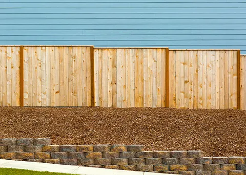 Segmental block retaining wall below a new wood privacy fence