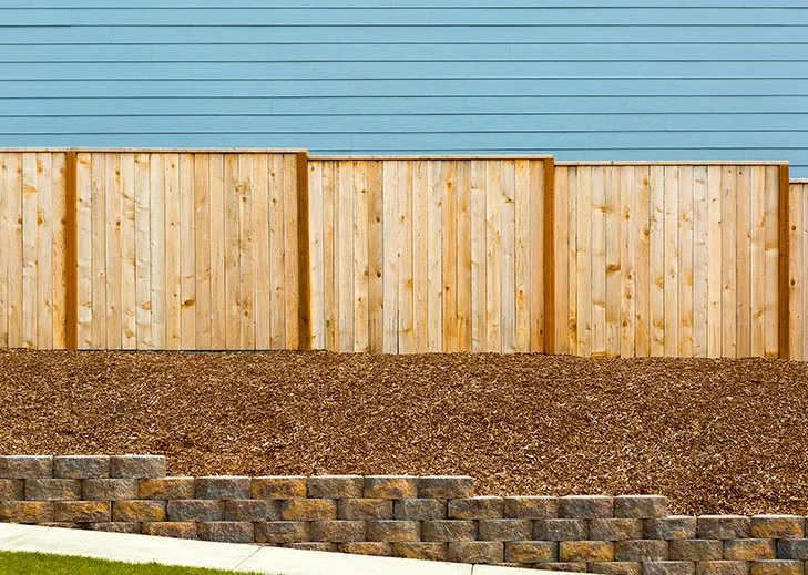 Segmental block retaining wall below a new wood privacy fence
