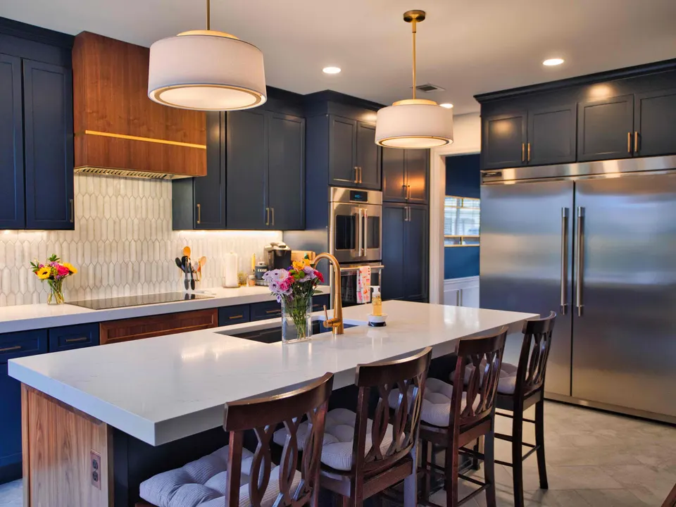 Kitchen with navy shaker cabinets, a walnut-trimmed island with white quartz, drum pendants and a built-in refrigerator