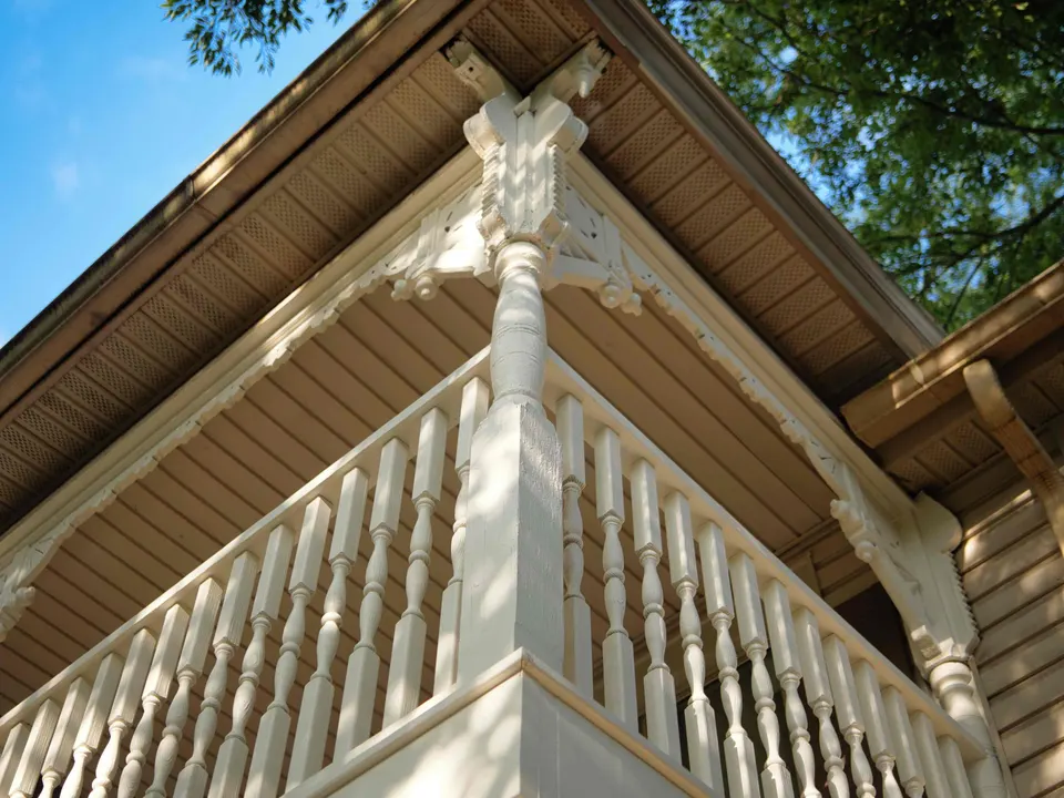 Corner of a restored balcony with turned spindles and decorative corbels