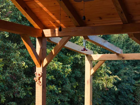 Exposed timber beams and knee braces under a pine ceiling