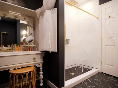 Bathroom with a vintage vanity table, white subway-tile shower and black marble-look floor tile