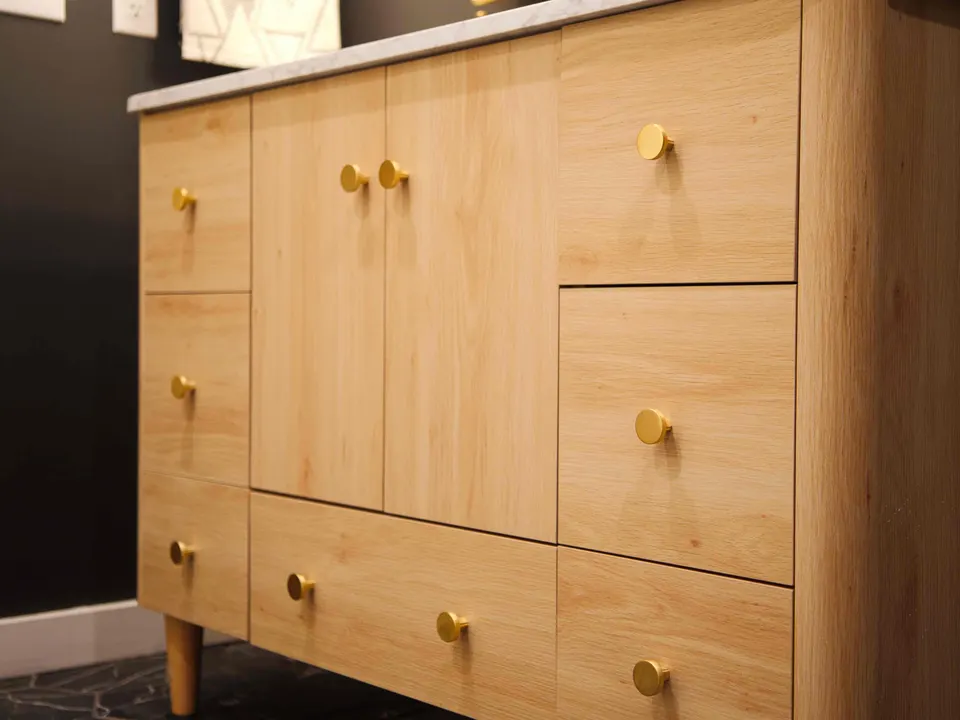 Light oak vanity with flat-panel drawers, brass knobs and tapered legs