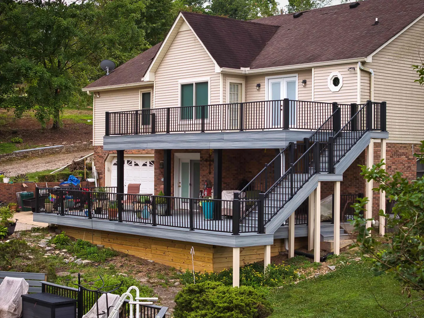 Two-level deck with black railings and a wide staircase on the back of a two-story home