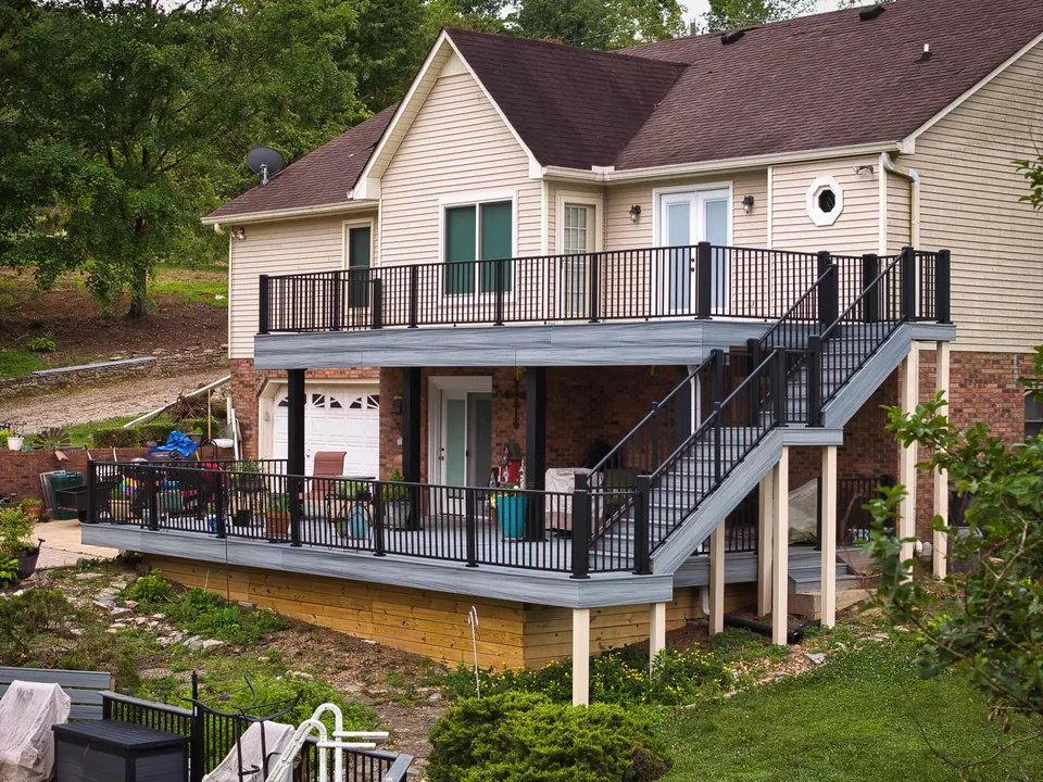 Two-level deck with black railings and a wide staircase on the back of a two-story home