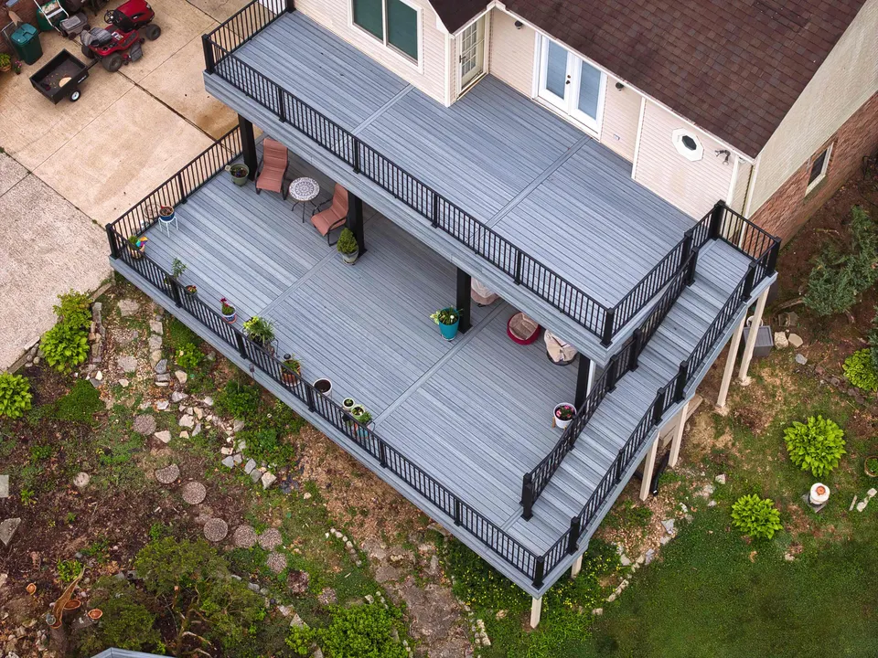 Aerial view of a two-level gray composite deck with black aluminum railings and a side staircase