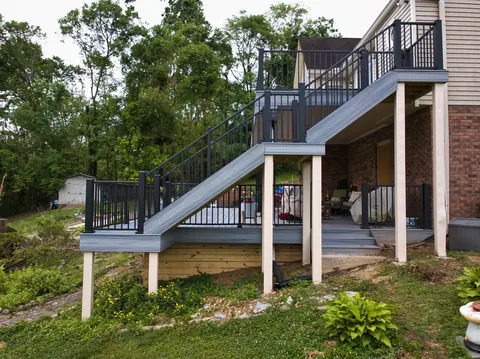 Composite staircase with black railings connecting an upper deck to a lower deck