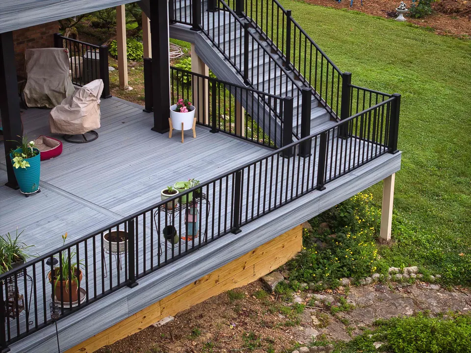 Lower deck with gray composite boards, black aluminum railings and a staircase