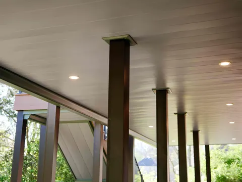 Covered patio beneath an upper deck with a finished ceiling, recessed lighting and black posts