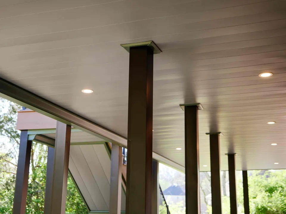 Covered patio beneath an upper deck with a finished ceiling, recessed lighting and black posts