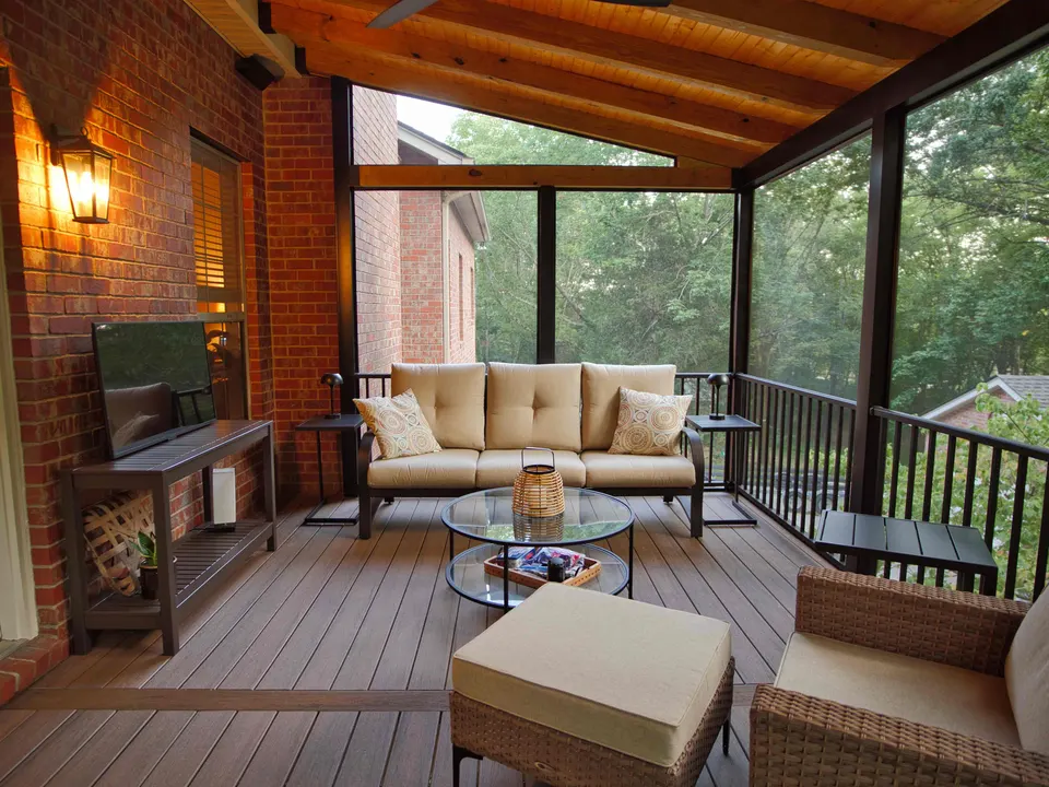 Screened porch with a stained wood ceiling, brick wall, mounted TV and outdoor seating