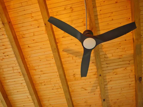 Vaulted tongue-and-groove porch ceiling with exposed rafters and a ceiling fan