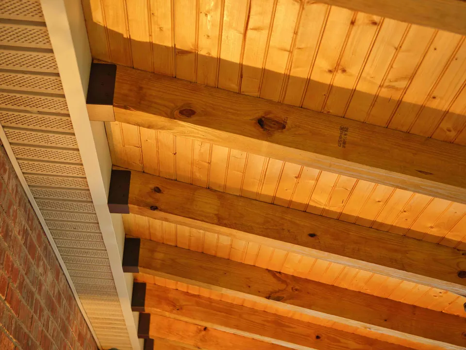 Exposed rafters and a tongue-and-groove ceiling meeting a brick wall