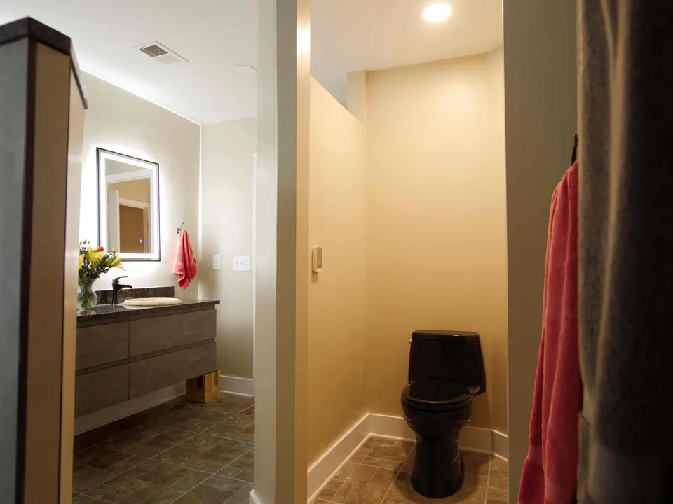 Bathroom with a floating vanity, backlit mirror and a separate water closet