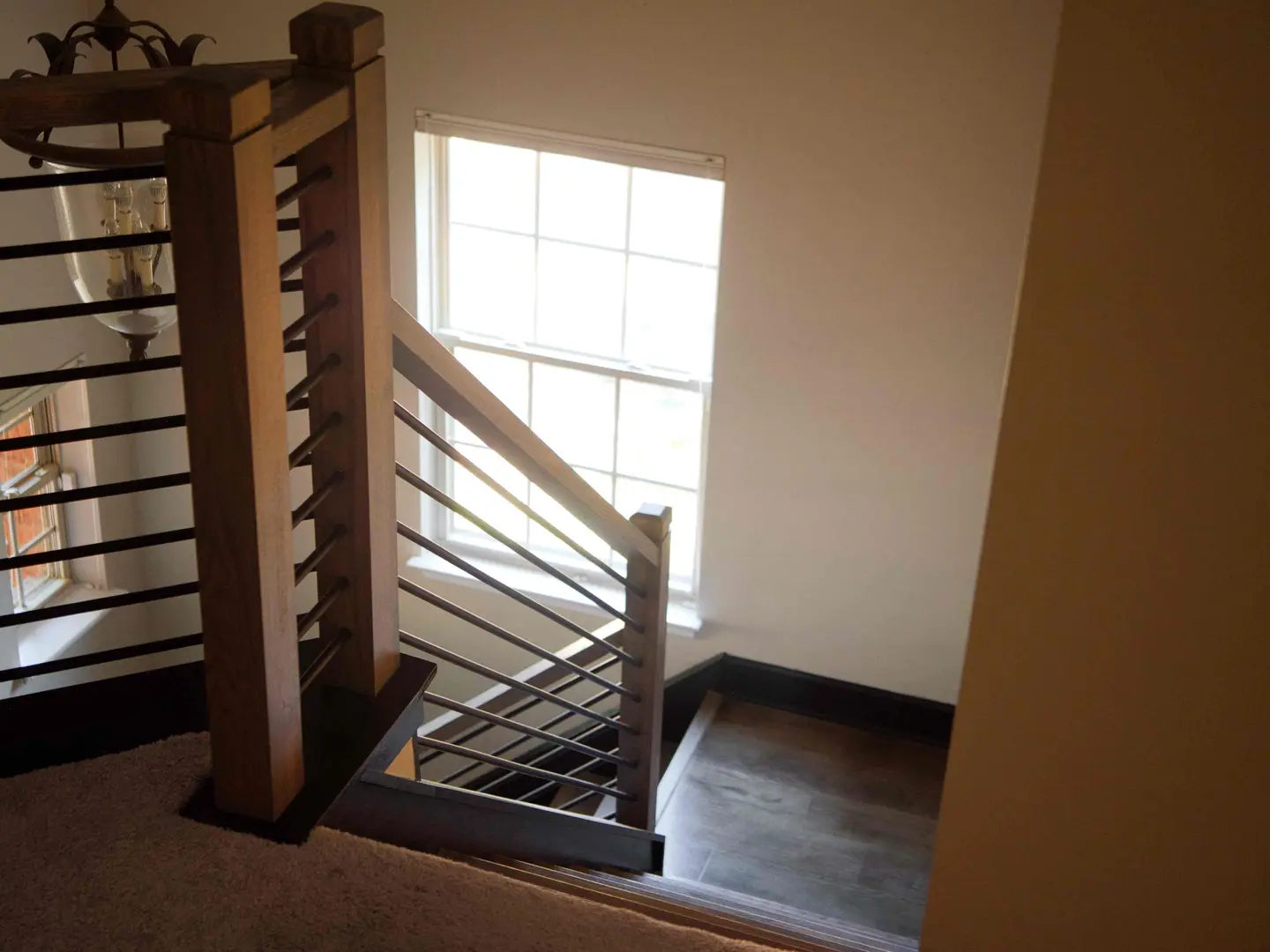 Staircase with a stained wood newel post and horizontal black metal balusters