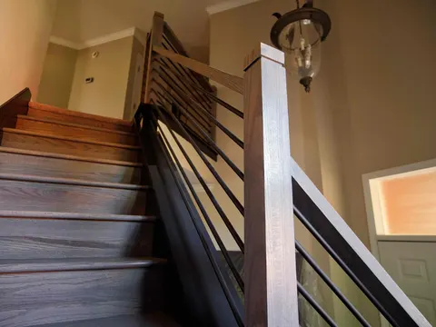 Stained wood stair treads with a horizontal metal railing and lantern pendant