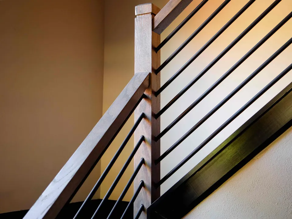 Wood newel post and handrail with horizontal black metal rods