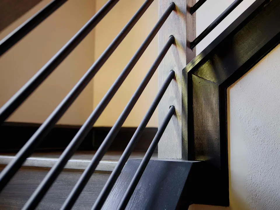 Horizontal metal balusters meeting a stained stair stringer