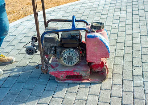 Plate compactor setting a new paver patio