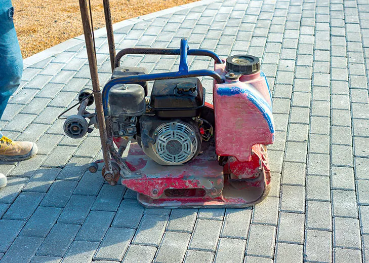 Plate compactor setting a new paver patio