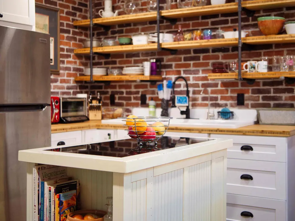Kitchen with an exposed brick wall, pipe-and-wood open shelving, butcher-block counters and a white island