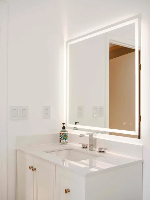 White shaker vanity with a quartz top, chrome faucet and backlit mirror