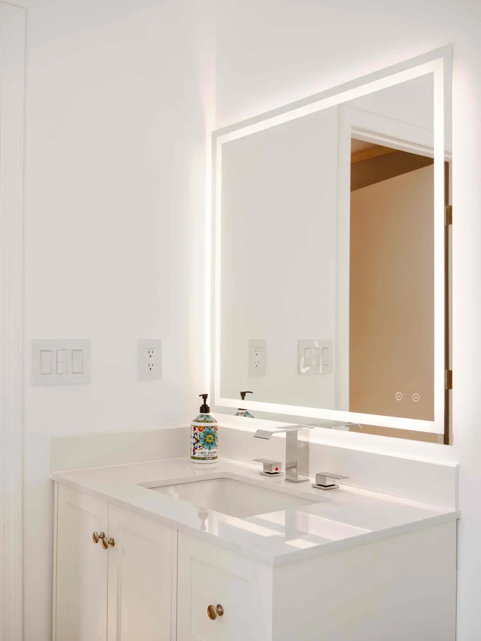 White shaker vanity with a quartz top, chrome faucet and backlit mirror