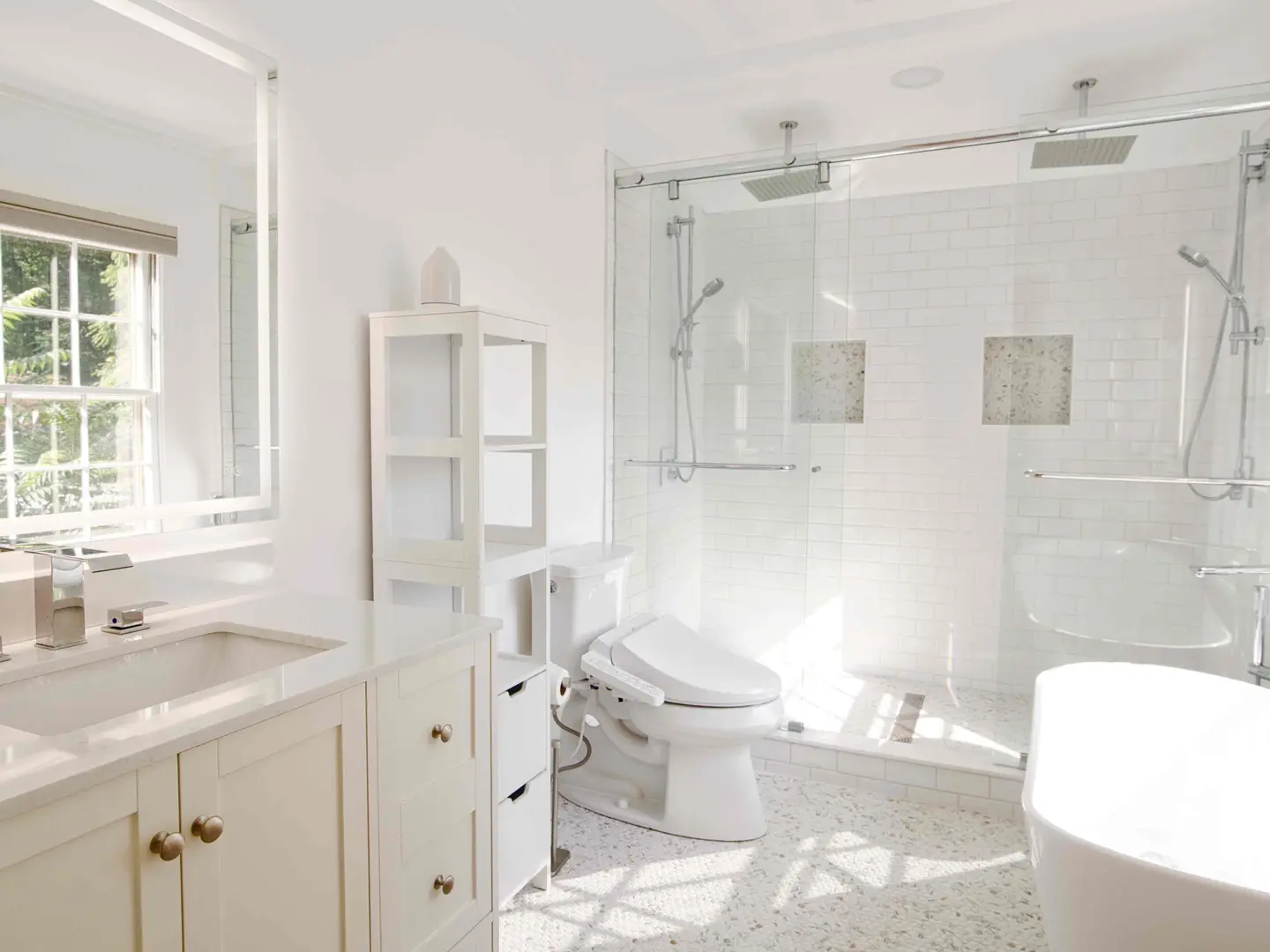 Primary bathroom with a two-person walk-in shower behind sliding frameless glass, a freestanding tub and a white vanity
