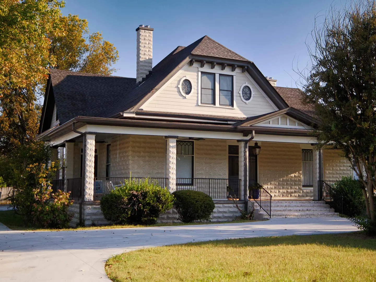 Renovated historic home with a deep front porch, stone-block columns and oval windows in the gable