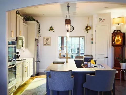Navy kitchen island with a concrete top and upholstered stools, seen through an arched opening