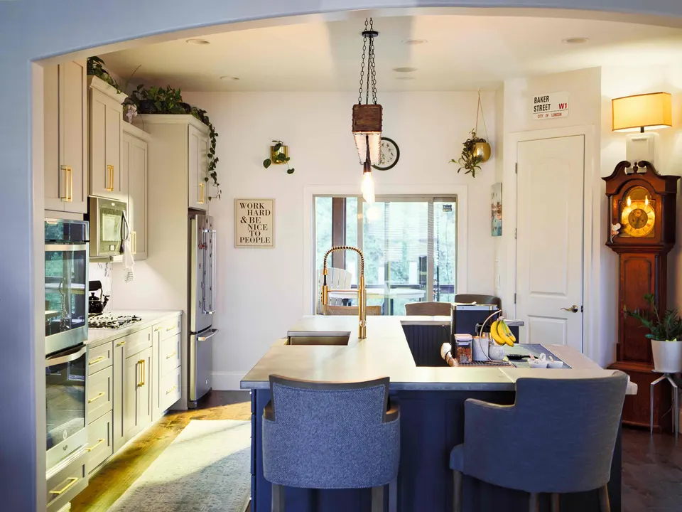 Navy kitchen island with a concrete top and upholstered stools, seen through an arched opening