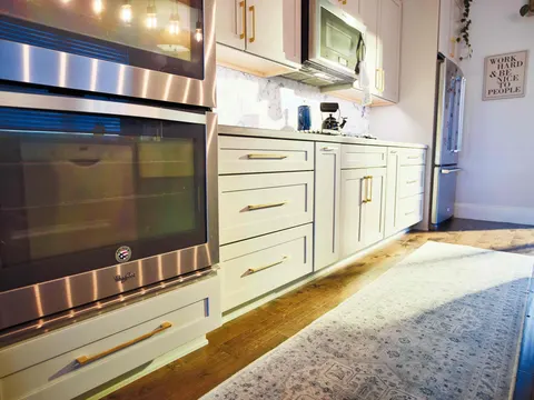 Double wall ovens and white shaker cabinets with brass pulls